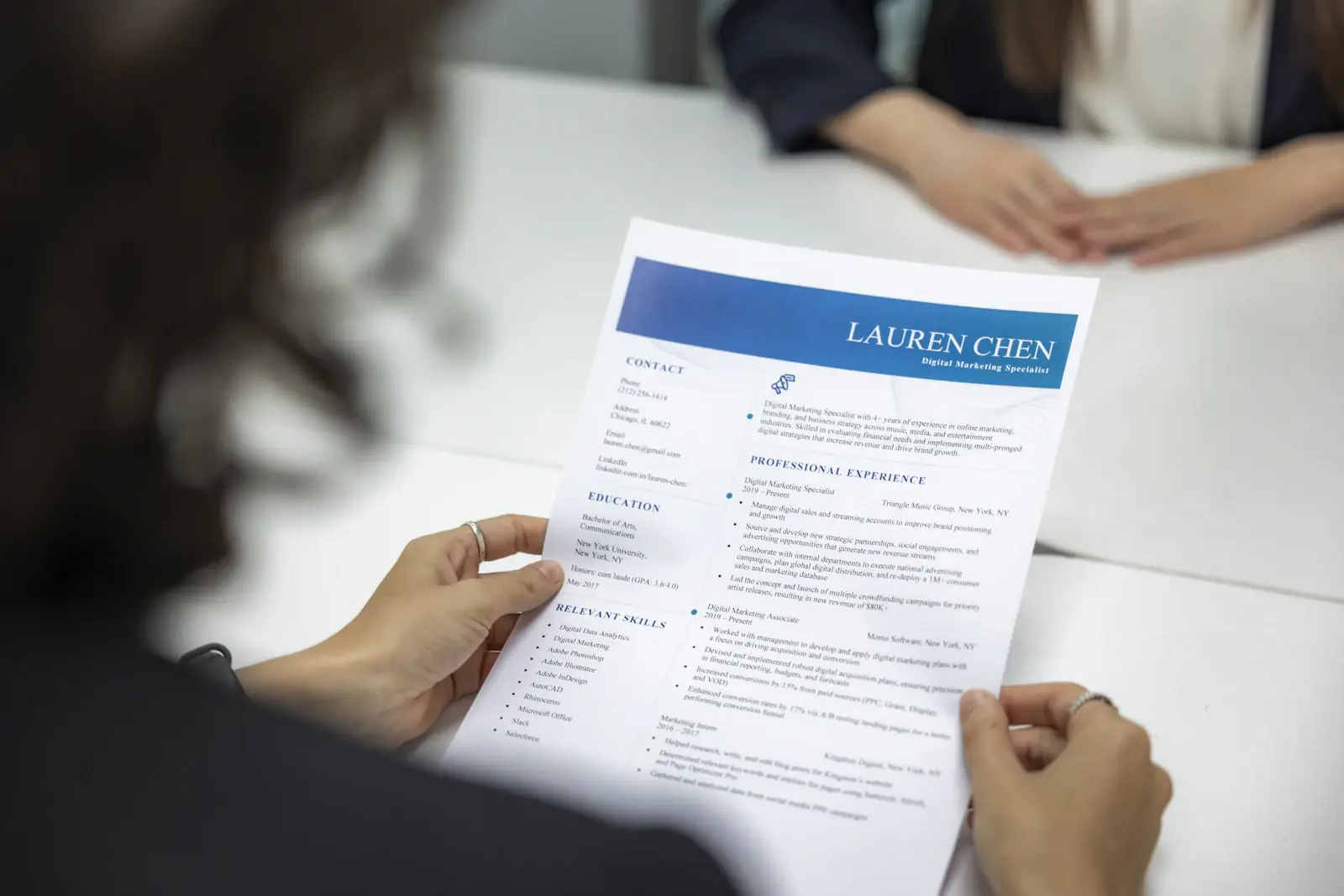 Iemand houdt een geprint cv vast tijdens een gesprek aan tafel
